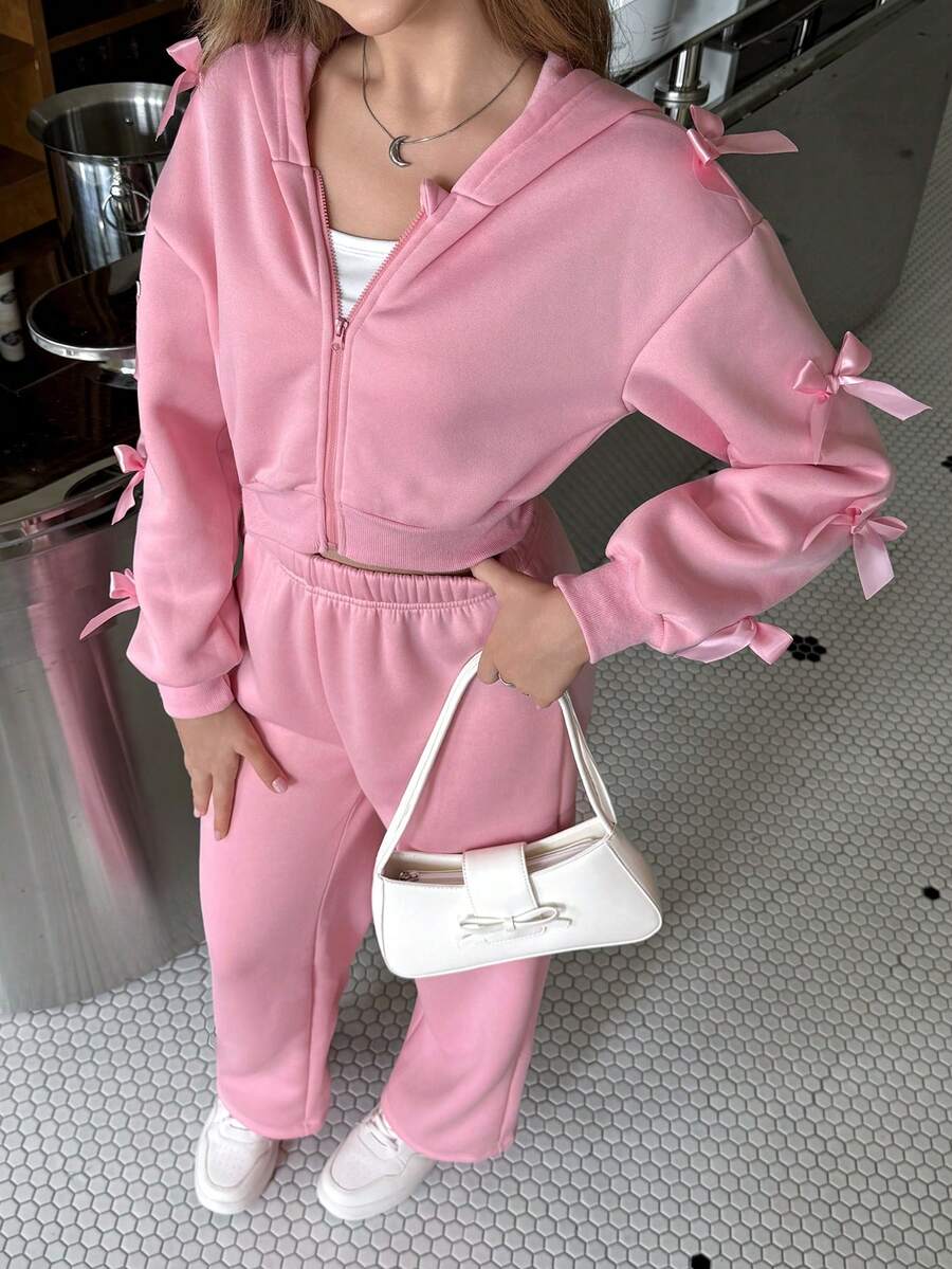 SHEIN 这款少女甜美风粉色连帽三件套，包含外套和裤子，采用柔软细腻的面料制成，带有连帽设计。服装上饰有立体蝴蝶结，增添俏皮感。腰部采用收腰设计，贴合身形。袖口采用常规款式，穿着舒适。内搭白色背心。 - 粉色 - 查看 1