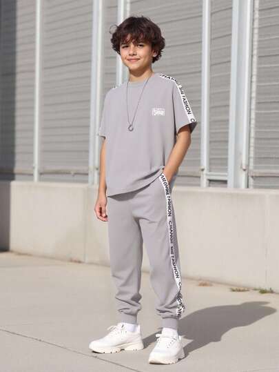 Vacaura 2 件/套大童休闲拼布字母带圆领 T 恤搭配拼布字母带侧条纹慢跑裤套装，适合日常穿着