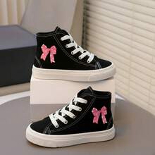 Tenis botín infantiles de tela con gráficos perfectos para actividades escolares, paseos, días casuales y juegos al aire libre. Agujetas blancas y gráficos laterales divertidos, que aportan estilo, dinamismo y personalidad al outfit diario. Fabricados en lona transpirable de alta resistencia, con suela de caucho flexible. Estilo urbano, deportivo y casual, ideal para la temporada Primavera-Verano, combinando fácilmente con jeans, shorts o joggers. Moños tenis de niña - Negro2 - Ver 1