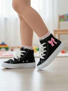 Tenis botín infantiles de tela con gráficos perfectos para actividades escolares, paseos, días casuales y juegos al aire libre. Agujetas blancas y gráficos laterales divertidos, que aportan estilo, dinamismo y personalidad al outfit diario. Fabricados en lona transpirable de alta resistencia, con suela de caucho flexible. Estilo urbano, deportivo y casual, ideal para la temporada Primavera-Verano, combinando fácilmente con jeans, shorts o joggers. Moños tenis de niña - Negro2 - Ver 2
