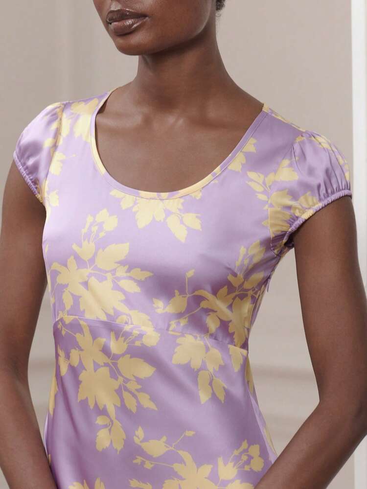 Vestido de satén largo con estampado floral amarillo sobre un fondo lila con mangas cortas y cuello redondo