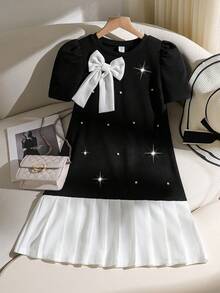 一件春夏温柔优雅连衣裙，短袖、圆领、泡泡袖拼接中长连衣裙，专为可爱时尚的女孩设计。非常适合日常通勤和下午茶场合。这款撞色优雅连衣裙以黑色为底，饰以珍珠，并配有立体白色蝴蝶结装饰和褶裥下摆。 - 黑色 - 查看 3