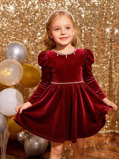 Sparklyn Denna underbara sammetsklänning för små flickor har eleganta bubbelärmar, fina pärlutskämt och en böljande A-linjeformad silhuett – perfekt för att förvandla din lilla till en charmig prinsessa på fester eller speciella tillfällen.