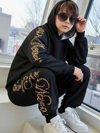 两件套青少年男童休闲街头风字母印花连帽衫和黑色长裤套装，适合秋冬季休闲、户外、上学、聚会等场合。