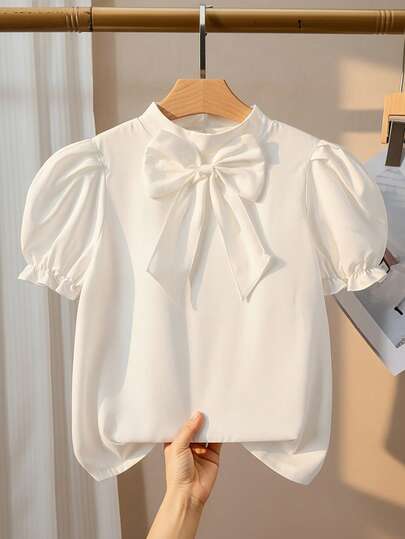 Teen Girl Summer Tops,Summer,Squishy,A Short-Sleeved, Pleated, Puffed, White Shirt With A Large Bow At The Collar For A Young Woman Is Comfortable, Fashionable, Elegant And Sweet. It Is Suitable For Daily And Festival Wear In Summer And For The Festival In The Middle East. Blouses, White Bow Shirt, Bow Shirt, Puffy Sleeve Blouses, White Top With Bows