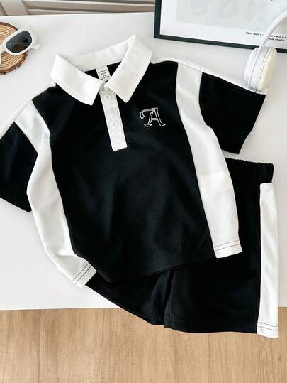 Genkimix Kids Set de 2 piezas: Camisa polo de manga corta con diseño de empalme en negro y blanco y pantalones cortos deportivos con empalme de color para niños. El Body principal es en negro, el cuello, la cartera y los lados están empalmados con tela blanca, con un gráfico de la letra A blanca en el pecho. Diseño de cuello vuelto con dos botones blancos. Estilo sencillo y deportivo, adecuado para todas las estaciones, para juegos diarios, salidas, trotar, etc.
