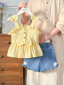 SHEIN Vintaside Kids Younggirl – Ten dwuczęściowy komplet składający się z żółtego topu halter i dżinsowych szortów z wysokim stanem z kieszeniami na wiosnę i lato jest uroczy, uroczy i uniwersalny. Tkanina o średniej grubości, ozdobiona falbankami i trójwymiarowymi kwiatowymi zdobieniami. Guziki z nadrukiem w panterkę dodają charakteru retro. Zestaw nadaje się do szkoły, na wycieczki, na wakacje, do relaksu w domu i na imprezy. - Żółty - Zobacz 5