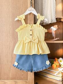 SHEIN Vintaside Kids Younggirl – Ten dwuczęściowy komplet składający się z żółtego topu halter i dżinsowych szortów z wysokim stanem z kieszeniami na wiosnę i lato jest uroczy, uroczy i uniwersalny. Tkanina o średniej grubości, ozdobiona falbankami i trójwymiarowymi kwiatowymi zdobieniami. Guziki z nadrukiem w panterkę dodają charakteru retro. Zestaw nadaje się do szkoły, na wycieczki, na wakacje, do relaksu w domu i na imprezy. - Żółty - Zobacz 3
