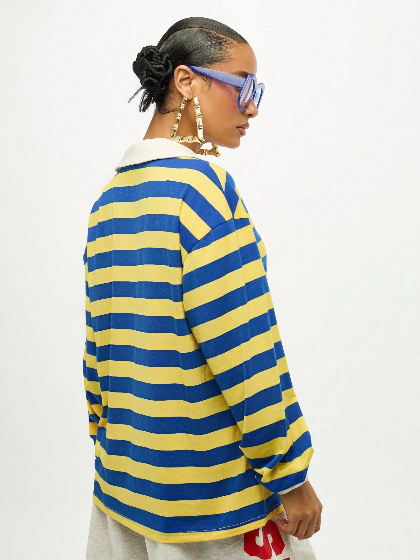 Blusa oversized listrada com decote em V e detalhe de amarração.