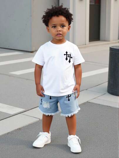 Set de 2 piezas: Parte superior de punto blanca de manga corta con cuello redondo y decoración gráfica negra, emparejada con shorts vaqueros negros desgastados de cintura elástica, para niños de 4 a 7 años, para uso en la calle, al aire fotografía
