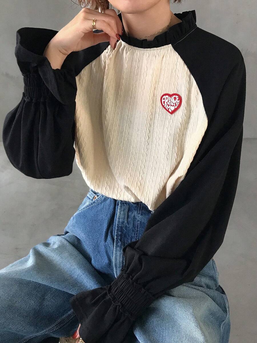 FRIFUL Camiseta holgada de manga larga con cuello de tortuga medio, mangas raglán de color contrastante, volantes y etiqueta de punto con corazón, estilo casual de calle para mujer - Negro - Ver 1