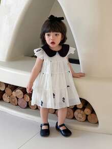 SHEIN Vestido negro de patchwork para niña este verano con cuello de bebé y pequeñas mangas voladoras que presenta un estilo de país elegante, dulce y retro. La tela tejida es de grosor moderado y cómoda. Los estampados florales del vestido son exquisitos y delicados. El corte holgado en línea A y el bajo con volantes lo hacen adecuado para la escuela, tomar fotos y registrarse, vacaciones, relajarse en casa y asistir a fiestas. - Blanco y Negro - Ver 7