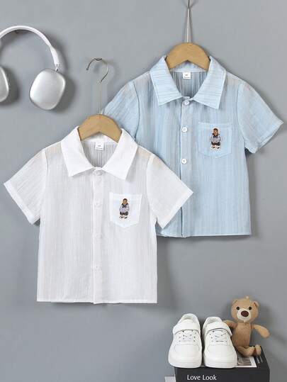 两件装男童小熊刺绣衬衫，白色和浅蓝色可选，翻领带胸袋，宽松版型方便活动，简约又不失趣味的设计，适合周末郊游、家庭聚会和返校穿着。