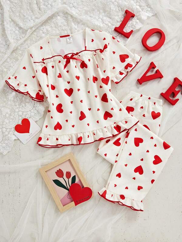 女童两件套睡衣：短袖上衣，饰有蝴蝶结和爱心印花，荷叶边下摆；宽松长裤，荷叶边下摆。