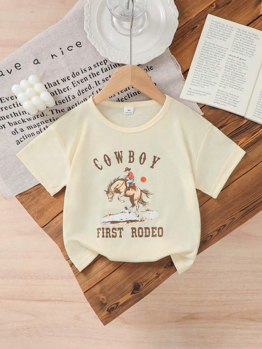 Genkimix Kids 女童宽松圆领短袖上衣，白色底，印有“COW BOY FIRST RODEO”复古牛仔骑马图案，时尚吸睛。适合年轻女孩参加西部主题派对、户外探险、夏季日常穿着，尽显复古美式风情。 - 白色 - 查看 1
