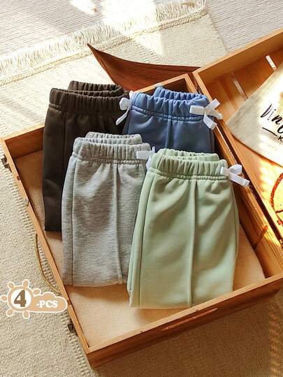 SHEIN Vintaside Kids Conjunto de 4 piezas de pantalones largos de corte recto para bebé niño este otoño e invierno, con estilo casual y deportivo en multicolor. Presenta una cintura elástica de talle alto decorada con lazos de cinta blanca. Disponible en cuatro colores: gris claro, verde, azul y gris oscuro.