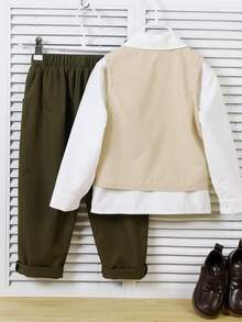 两件套儿童梭织背心和长裤绅士套装，主打复古工装风格。上衣为浅卡其色不对称翻领背心，饰有深色纽扣，左胸设有纽扣装饰口袋和白色滚边。下装为深绿色长裤，整体呈现出质朴的手工质感，适合儿童表演、复古主题服装等场合。 - 卡其色 - 查看 2