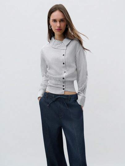 Nöista 条纹长袖衬衫，不对称纽扣前襟，修身剪裁。这款别致休闲衬衫非常适合日常穿着、工作装扮和春假叠穿，可轻松搭配牛仔裤或修身长裤。