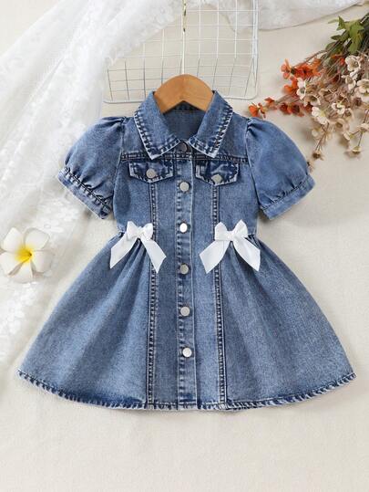女童浅色水洗牛仔连衣裙，翻领泡泡袖设计，金属纽扣前襟，腰间蝴蝶结装饰，A字廓形，甜美、休闲、公主风皆宜，春夏穿着，适合日常穿着、生日派对、家庭出游、假日拍照等场合。