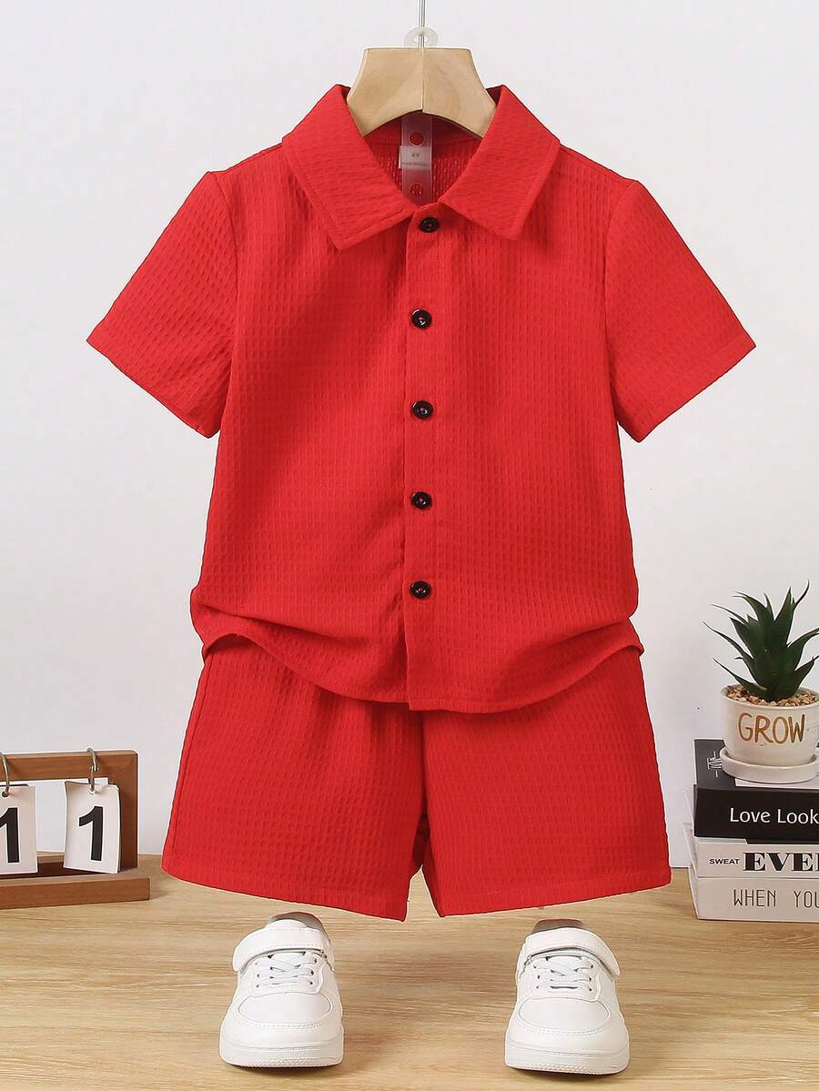 SHEIN 男童纯色Polo领衬衫短裤套装,夏季款。这套童装以鲜艳的红色为主色调。上衣为短袖Polo领衬衫,搭配黑色纽扣,简约优雅。下装为红色短裤。整体风格整洁正式,适合儿童在演出、庆典等正式场合穿着。鲜艳的红色更增添了一份活泼喜庆的气氛。 - 紅色 - 查看 1