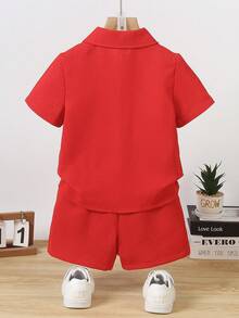 SHEIN 男童纯色Polo领衬衫短裤套装，夏季款。这套童装以鲜艳的红色为主色调。上衣为短袖Polo领衬衫，搭配黑色纽扣，简约优雅。下装为红色短裤。整体风格整洁正式，适合儿童在演出、庆典等正式场合穿着。鲜艳的红色更增添了一份活泼喜庆的气氛。 - 紅色 - 查看 2