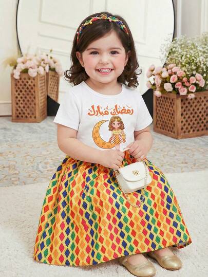 SHEIN Outfit i festivalstil för unga flickor i mellanöstern - Vit t-shirt med arabisk text och månflickgrafik, färgglad diamantmönstrad kjol med stor rosettdesign, festlig och exotisk look lämplig för firanden, fester och helgdagar. T-shirten har normal tjocklek, kjolen har kvalitetstyg men är inte tung.