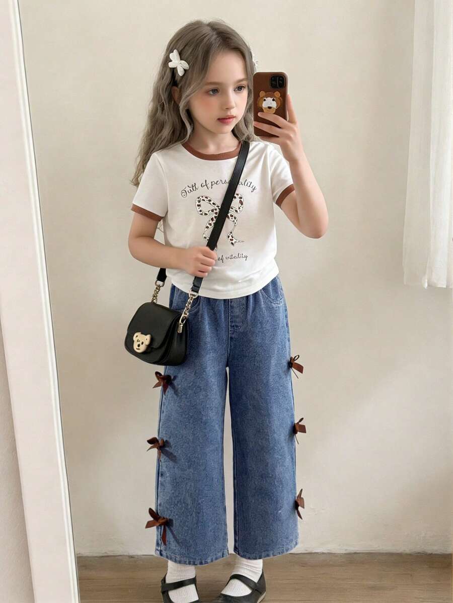 Bộ áo thun cho bé gái, áo thun cổ tròn với cổ áo và tay áo phối màu tương phản, in hình nơ trước và sau, phối cùng quần jeans thường ngày, quần jeans có đinh tán và nơ bên hông, kiểu dáng đơn giản và thời trang, họa tiết nơ tạo điểm nhấn thanh lịch, thích hợp cho các buổi đi chơi, bộ 2 món. - trắng - Xem 1
