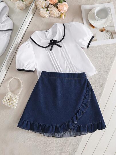 两件套少女学院风套装，春夏款 - 白色泡泡袖针织上衣，饰有蝴蝶结，搭配深蓝色A字牛仔裙，裙摆饰有荷叶边，面料柔软舒适，适合上学、通勤、休闲穿着。