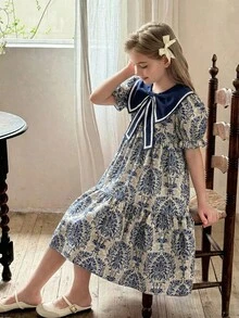 SHEIN Vintaside Kids 这款女童夏季波西米亚风甜美度假连衣裙，采用蓝色碎花印花，配有大蝴蝶结领、短袖和宽松的及膝裙摆。非常适合日常穿着、购物、海滩郊游、度假等场合。 - 彩色 - 查看 1