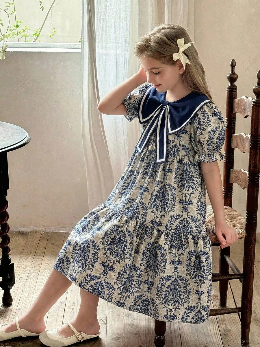 SHEIN Vintaside Kids 这款女童夏季波西米亚风甜美度假连衣裙，采用蓝色碎花印花，配有大蝴蝶结领、短袖和宽松的及膝裙摆。非常适合日常穿着、购物、海滩郊游、度假等场合。 - 彩色 - 查看 1