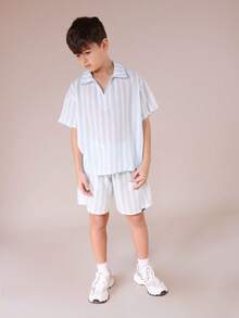 Bộ đồ thể thao SUMWON cho bé trai gồm áo sơ mi ngắn tay kẻ sọc và quần short cùng màu, thích hợp cho mùa hè, kiểu dáng thường ngày. Chất liệu vải nhẹ, có họa tiết, áo cổ bẻ cài nút và quần short cạp chun, lý tưởng cho kỳ nghỉ. - Xanh và trắng - Xem 5