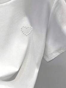 修身短款白色T恤，珍珠爱心图案，适合青少年女孩，春、夏、秋季穿着，日常休闲时尚，适合13-16岁女孩。