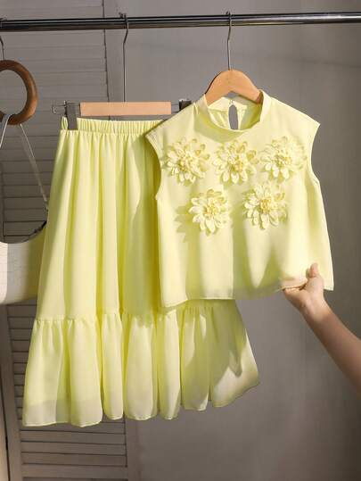 SHEIN This Is A Set Consisting Of Two Items For Girls: A Short A-Line Vest With A Standing Collar And No Sleeves, Featuring Three-Dimensional Floral Decorations On The Front, And A Loose A-Line Skirt With An Elastic Waistband. This Sweet And Feminine Two Pieces Set Is Perfect For Summer.