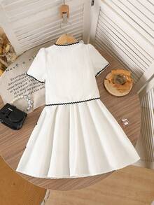 SHEIN Bộ váy hai dây màu trắng kem kiểu Pháp cổ điển dành cho bé gái, gồm váy và áo khoác cardigan tay ngắn. Váy được làm từ vải kẻ sọc dọc mềm mại, có phần gấu váy xếp tầng với viền lượn sóng màu đen. Áo khoác cardigan có cổ tròn được trang trí bằng họa tiết hoa 3D màu đen và viền lượn sóng đen. Thiết kế tổng thể tươi mới, tinh nghịch với chút ngọt ngào cổ điển. Váy nhẹ và áo khoác cardigan mỏng phù hợp cho những buổi đi chơi thường ngày, dạo chơi công viên hoặc những buổi họp mặt gia đình vào mùa hè. - trắng - Xem 2