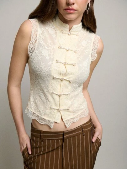 Nöista 这款无袖立领中式蕾丝上衣，饰有珍珠纽扣和花卉蕾丝，柔和的配色和轻盈透气的面料融合了现代中式风情和当代优雅，使其成为春假和初春穿搭中独特时尚的叠穿单品。