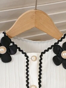SHEIN Bộ váy hai dây màu trắng kem kiểu Pháp cổ điển dành cho bé gái, gồm váy và áo khoác cardigan tay ngắn. Váy được làm từ vải kẻ sọc dọc mềm mại, có phần gấu váy xếp tầng với viền lượn sóng màu đen. Áo khoác cardigan có cổ tròn được trang trí bằng họa tiết hoa 3D màu đen và viền lượn sóng đen. Thiết kế tổng thể tươi mới, tinh nghịch với chút ngọt ngào cổ điển. Váy nhẹ và áo khoác cardigan mỏng phù hợp cho những buổi đi chơi thường ngày, dạo chơi công viên hoặc những buổi họp mặt gia đình vào mùa hè. - trắng - Xem 5
