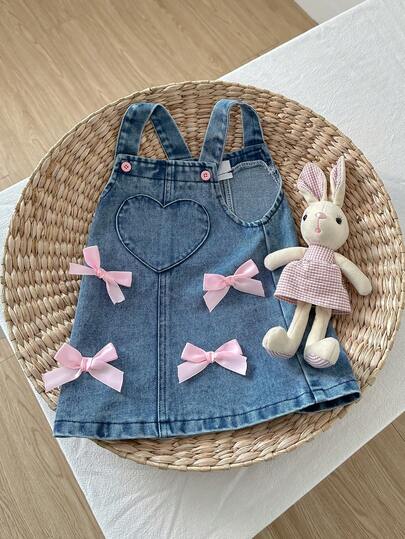 SHEIN Playful Pals 1 pieza Vestido peto de mezclilla azul claro lavado para niñas con bolsillos con forma de corazón y decoración de moño, falda de mezclilla casual y de moda, adecuado para salidas de verano, viajes, fotografía y diversas ocasiones