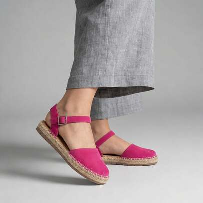 Alpargatas tipo sandalia para mujer, disponibles en negro, fucsia y miel, modelo casual confeccionado en textil suave con acabado aterciopelado, punta cerrada redondeada, correa ajustable al tobillo, estructura de suela de yute natural y base de goma flexible, costuras visibles tipo artesanal, plantilla acolchonada, diseño fresco de inspiración mediterránea pensado para combinar con vestidos, pantalones, faldas y looks veraniegos, aportando confort y un toque desenfadado en cada paso.