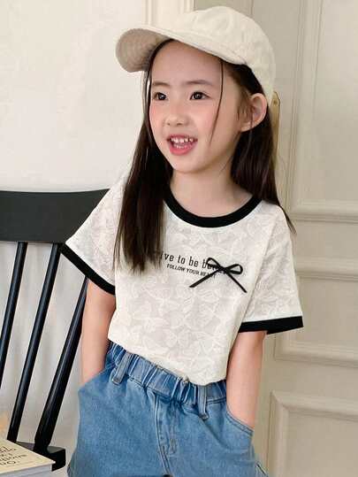 DAZY Camiseta casual de manga corta con cuello redondo, decoración de lazo y estampado de eslogan para niña joven