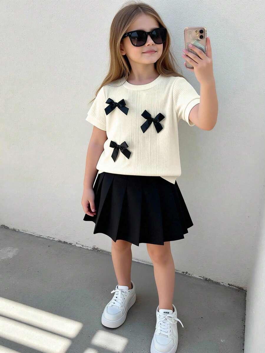 2pcs/Set Toddler Girls' T-Shirt And Skirt Set, Collegiate Style, Round Neck Short Sleeve Top With 3D Bow Decor, Paired With Black Pleated Skirt, Sweet And Casual Summer Outfit - Apricot - View 1