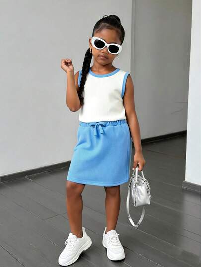 女童撞色背心运动裤套装，蓝白配色。上衣采用纹理针织面料，舒适透气，圆领无袖设计。下装为蓝色运动裤。整体造型时尚简约，适合外出、日常穿着、返校和聚会等场合。版型较为修身，适合返校和日常穿着。