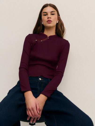 Nöista 这款优雅的黑色针织上衣采用柔软的罗纹面料，独特的非对称领口饰以白色撞色滚边和金属纽扣，尽显精致优雅。修身剪裁，既保暖又不失优雅，是冬日、圣诞晚宴或新年时尚造型的理想之选，也是女士冬季服装系列中的必备单品。