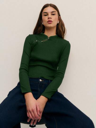 Nöista 这款优雅的黑色针织上衣采用柔软的罗纹面料，独特的非对称领口饰以白色撞色滚边和金属纽扣，尽显精致优雅。修身剪裁，既保暖又不失优雅，是冬日、圣诞晚宴或新年时尚造型的理想之选，也是女士冬季服装系列中的必备单品。