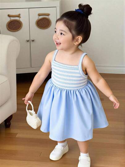 SHEIN Playful Pals 女婴吊带A字连衣裙。这款连衣裙采用吊带设计，简约优雅。A字裙摆更添活泼可爱之感。宽松版型适合各种身材。适合夏季海滩度假、户外野餐和休闲出行，让宝宝在展现独特魅力的同时，尽享轻松自在的时光。