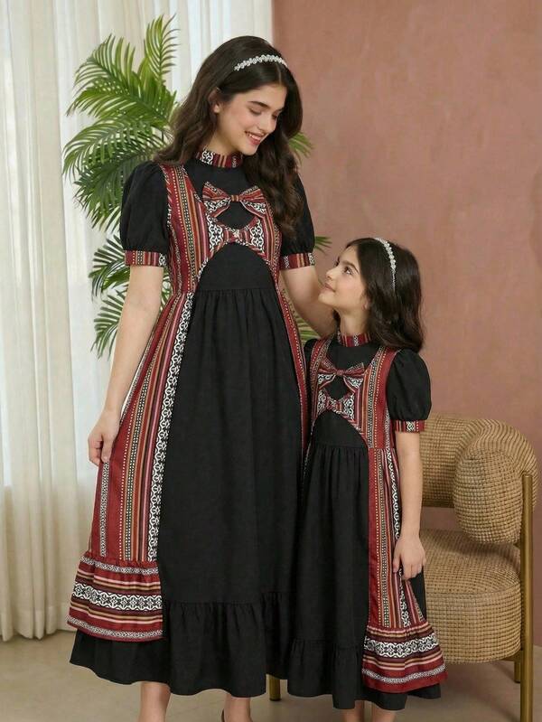 Ceci est un ensemble de deux pièces pour filles, composé d'une robe avec un petit col montant, des manches bouffantes et une décoration de nœud sur le devant du col. Les poignets et le col sont également ornés de motifs géométriques. De plus, il y a une veste longue à l'avant ouvert et avec un motif géométrique. Ensemble, ces deux pièces forment une tenue décontractée, prête pour les vacances, pour les filles en été.