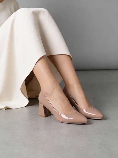 Zapatos de tacón medio y bloque disponibles en negro y nude, modelo clásico tipo salón de punta ligeramente estilizada, elegante acabado charolado que otorga un brillo sofisticado a cualquier atuendo, estructura firme con plantilla acolchada y suela resistente, tacón grueso cuadrado para soporte estable durante largas jornadas, interiores suaves y diseño atemporal que permite combinaciones versátiles en contextos formales o eventos cotidianos, adaptándose a diferentes estilos de temporada