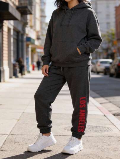 Pantalón jogger tipo sudadera unisex gris oscuro, tiro medio con resorte y cordón, puño en tobillo y estampado lateral "Los Angeles" en rojo, perfecto para streetwear, gym o outfit casual