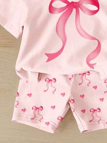 SHEIN 女婴休闲宽松圆领短袖T恤短裤套装（2件套），饰有可爱的爱心和蝴蝶结印花，适合春夏日常穿着、外出、居家、上学等场合。