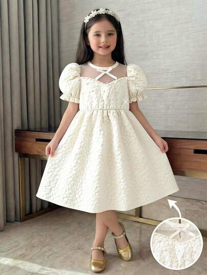 SHEIN 小女孩甜美公主风连衣裙，蓬松质感面料，心形领口饰有蝴蝶结，泡泡袖配荷叶边袖口，宽松可爱廓形，米色，适合休闲外出和派对，轻盈透气，春夏穿着。