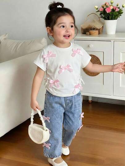 女童两件套夏季套装，甜美可爱清新休闲学院风穿搭推荐：白色圆领上衣，饰有手工粉色3D蝴蝶结，抽绳下摆打造自然褶皱效果；搭配浅蓝色水洗直筒牛仔裤，饰有蓬松蝴蝶结刺绣，适合日常、外出、上学等多种场合。白色和浅蓝色的配色清新柔和，蝴蝶结元素贯穿整套服装，是打造甜美风格的理想之选。